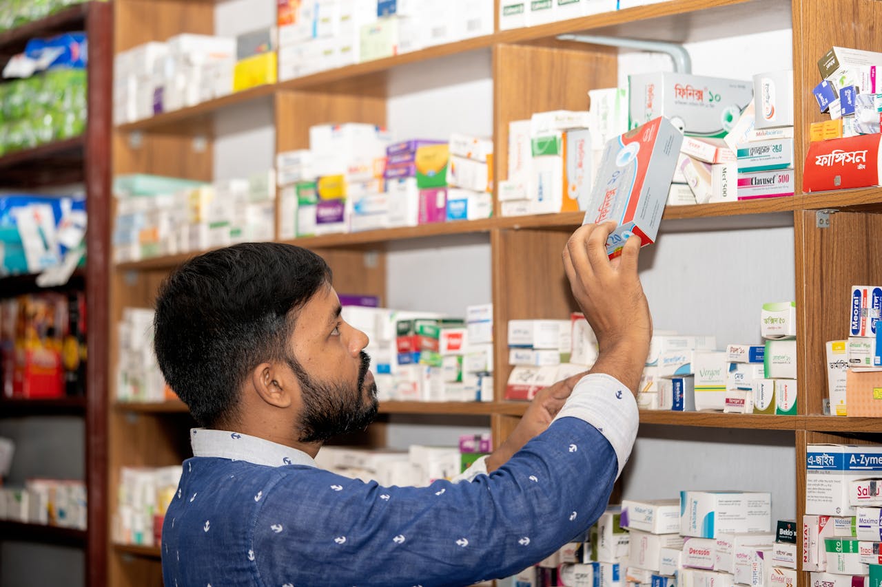about-us A pharmacist organizing medication on shelves in a pharmacy in Bangladesh.